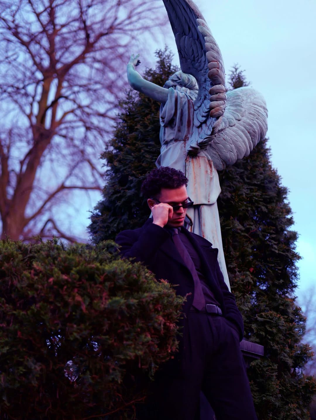 Leaning on the guardian angel in a black suit and tie - Holy Infa