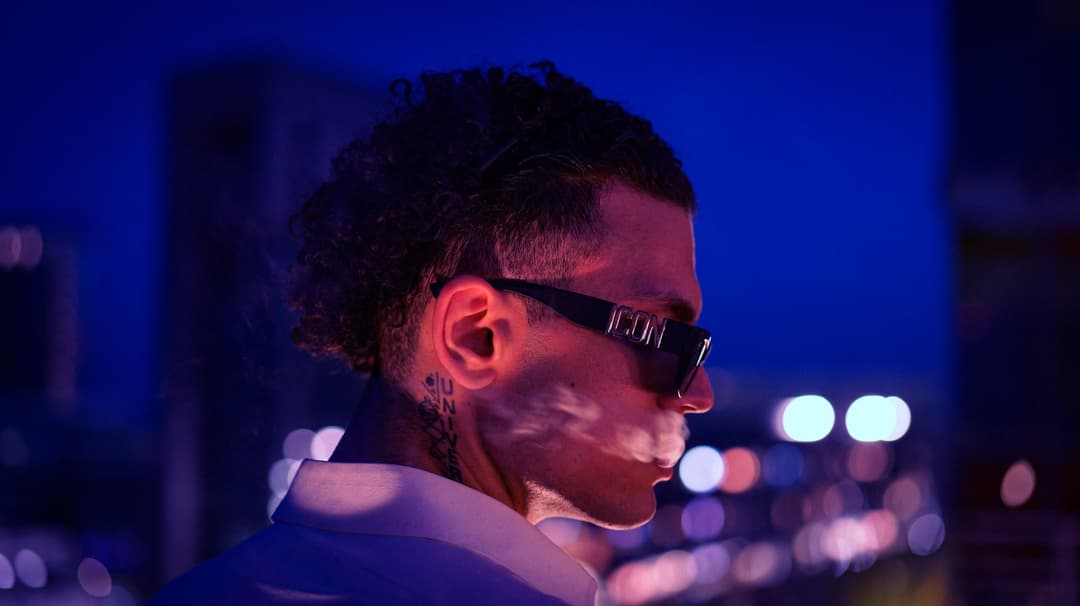 Side profile and cigar smoke with the city shining in the background - Holy Infa